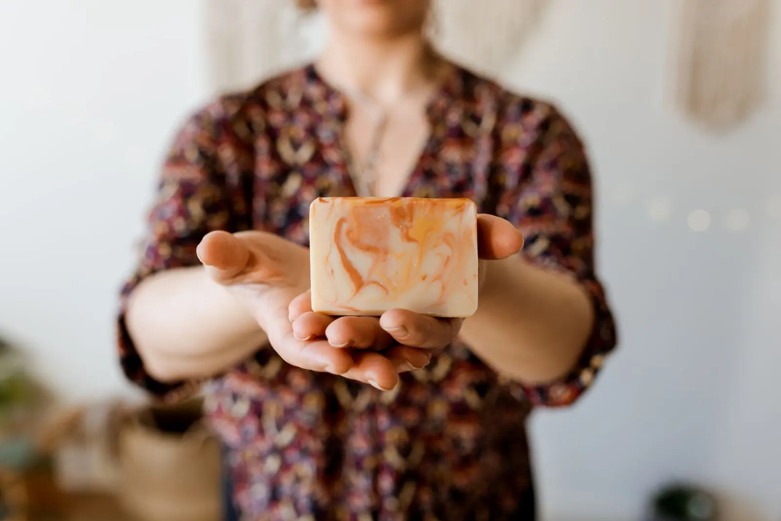 Élodie, savonnière, tient un savon artisanal marbré orange